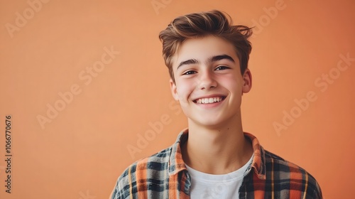 Portrait of smiling young Caucasian man wearing plaid flannel shirt against coral colored wall, copy space