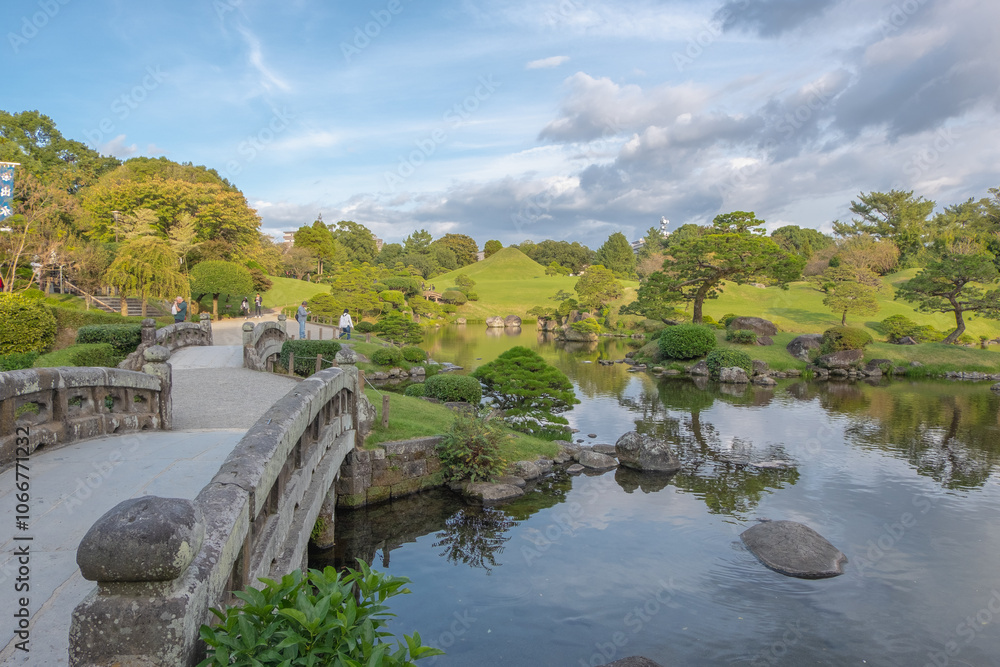 Suizenji Jojuen Garden, stone bridge in the garden with blue sky and cloud, Kumamoto, Kyushu, Japan Suizenji Jojuen Garden, stone bridge in the garden with blue sky and cloud, Kumamoto, Kyushu, Japan