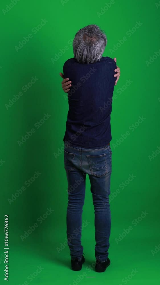 The senior Asian man standing on the green screen background. The senior Asian man standing on the green screen background.