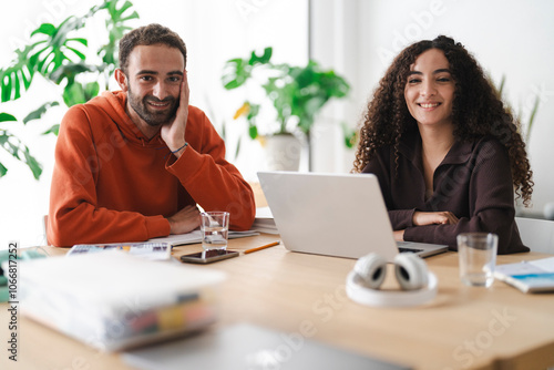 Two young adults share a smile across the table during a study session, bringing a sense of warmth and camaraderie to their learning environment. photo