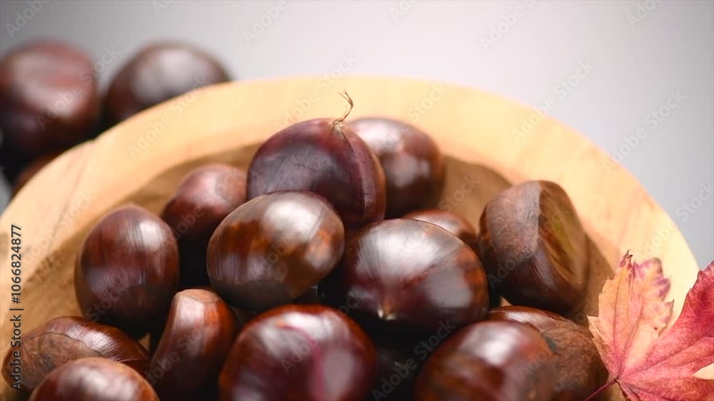 Chestnut, Fresh sweet chestnuts with autumn red leaves on black background, top view. Thanksgiving day. Edible chestnuts (Castanea sativa) rotating in wooden bowl. Top view. Close up Chestnut, Fresh sweet chestnuts with autumn red leaves on black background, top view. Thanksgiving day. Edible chestnuts (Castanea sativa) rotating in wooden bowl. Top view. Close up