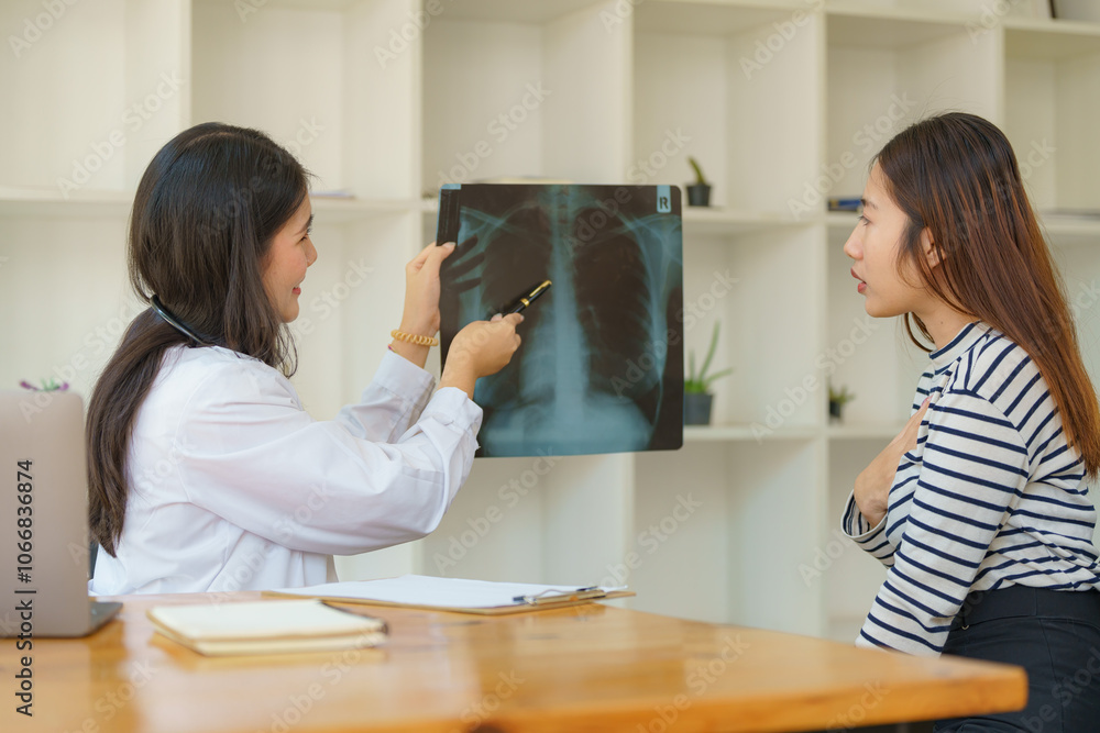 Asian female doctor explaining lung x-ray film of a female patient at the hospital. Asian female doctor explaining lung x-ray film of a female patient at the hospital.