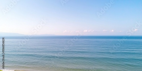 Calm ocean view under clear blue sky, serene waves gently lapping at the shore.