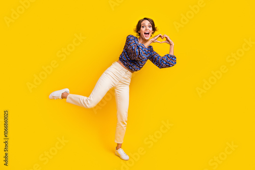 Full body size photo of young girl brown bob haired showing sympathy love sign standing one leg isolated on yellow color background photo