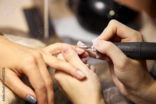 Women's manicure. Female hand undergoing a manicure procedure. The master does a women's manicure. A manicurist files a women's nails in a salon. Hygiene and hand care for woman. manicure design.