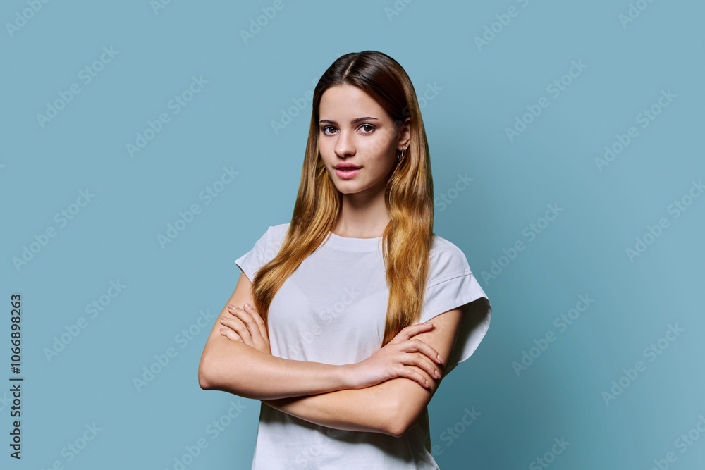 Beautiful young girl with crossed arms looking at camera on blue background Beautiful young girl with crossed arms looking at camera on blue background