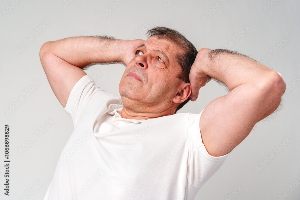 Elderly man stretching and relaxing indoors with a thoughtful expression and neutral background Elderly man stretching and relaxing indoors with a thoughtful expression and neutral background