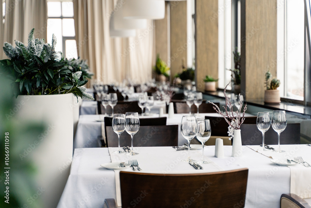 The restaurant features a stylish and contemporary interior complete with elegant table settings and vibrant plants.
