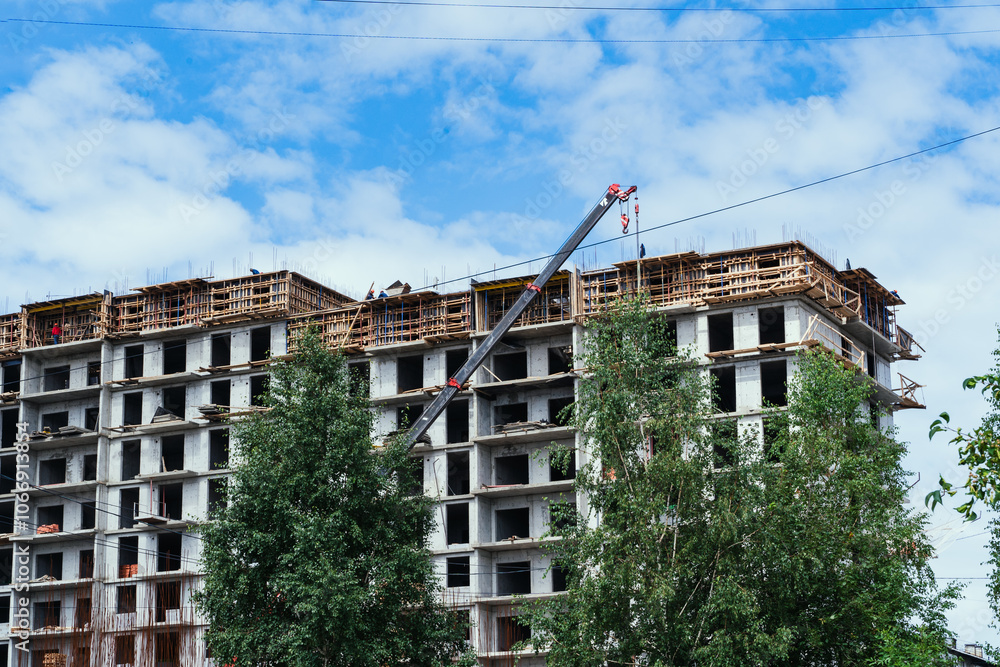 The ongoing construction of a multistory building features cranes and scaffolding raised overhead