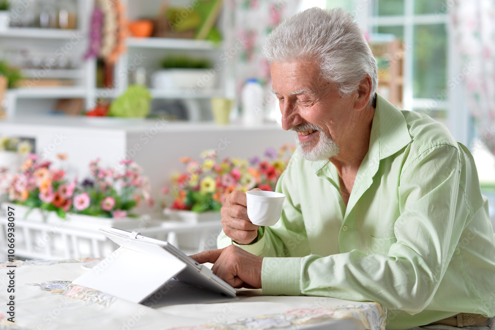 Elderly man posing at a table with a tablet Elderly man posing at a table with a tablet