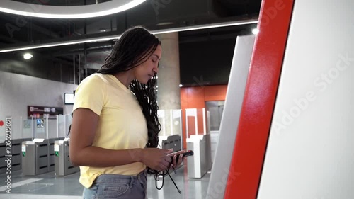 Young woman is buying a train ticket at a self-service terminal