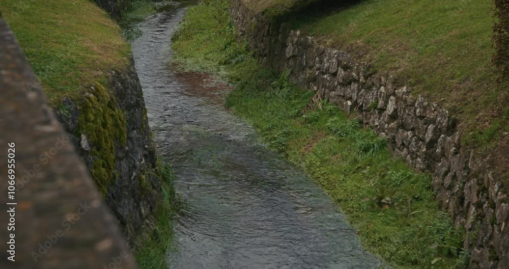 Clear stream flowing between mossy stone walls in Kumrovec, Croatia Clear stream flowing between mossy stone walls in Kumrovec, Croatia