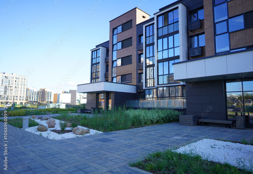 Obraz premium Stone on lawn at entrance of apartment residential buildings. Landscaping for urban spaces. Rock Garden Design. Rock Landscaping. Natural stone landscaping in home Front Yard. Shrub of thuja in yard.