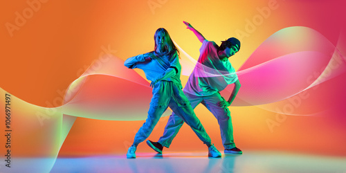 Creative design. Stylish man and woman dancing hip-hop in casual clothes on gradient background with abstract flowing elements. Concept of art of dance, choreography, youth culture