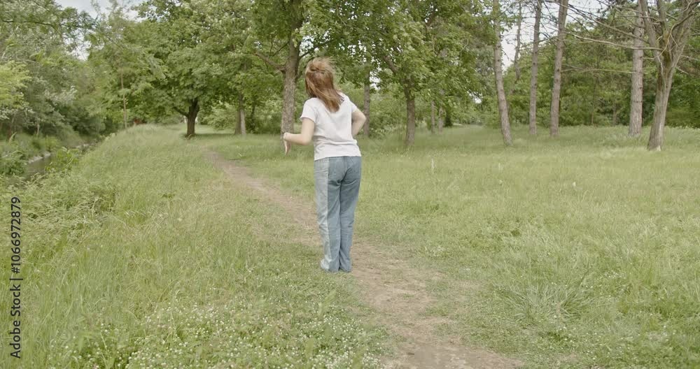 Carefree woman dances in a sunny park, enjoying the peace and quiet of nature. Carefree woman dances in a sunny park, enjoying the peace and quiet of nature.