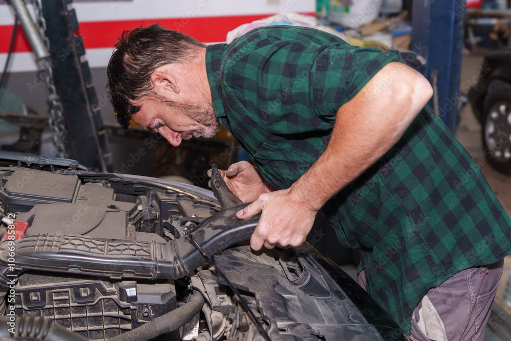 Mechanic inspecting car engine components in workshop Mechanic inspecting car engine components in workshop
