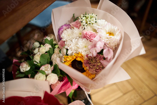 festive bouquet of flowers on the table. Glass vase with a bouquet of beautiful flowers on the table in the room. Place for text. Beautiful bouquet in a festive package on the table