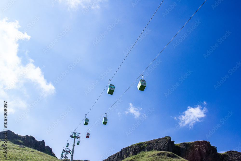 two green ski lifts are suspended in the air with a blue sky in the background. two green ski lifts are suspended in the air with a blue sky in the background.