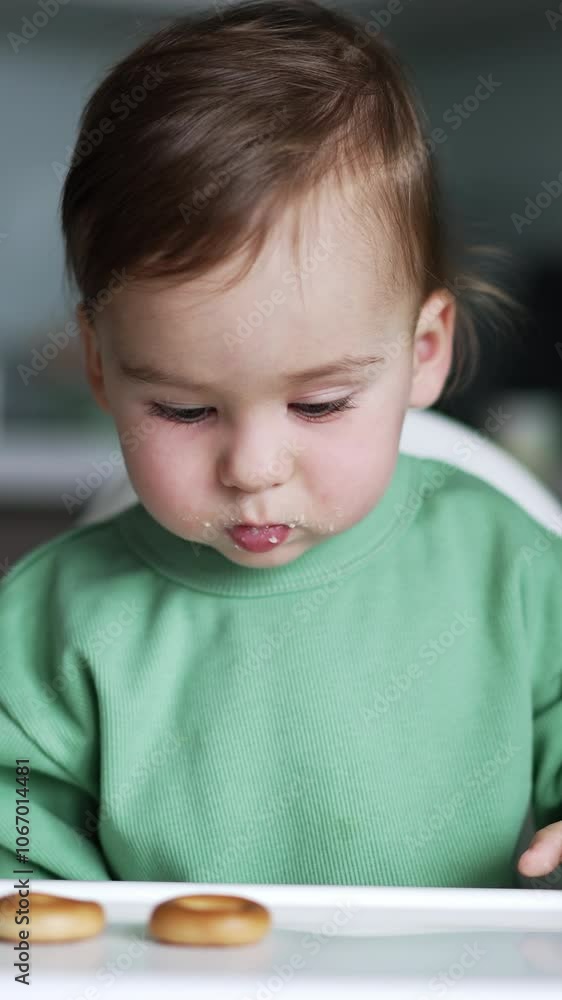 Cute little kid watching carefully his mom putting bagels in front of him. Loving parent playing with a child while feeding. Close up. Vertical video Cute little kid watching carefully his mom putting bagels in front of him. Loving parent playing with a child while feeding. Close up. Vertical video