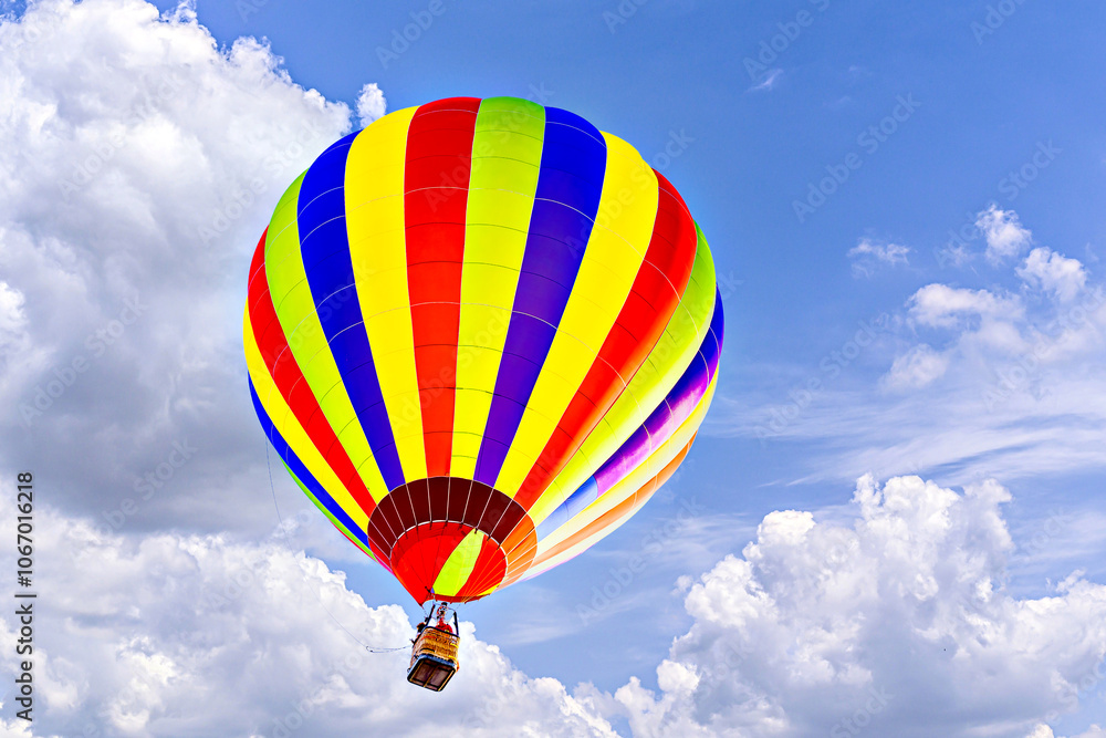 Fototapeta premium Colorful hot air balloon flying over blue sky with white clouds