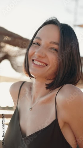 Slow motion close up of attractive young woman with bob haircut smiling happily at the camera during a sunny day. Happiness, youth and beauty concept.