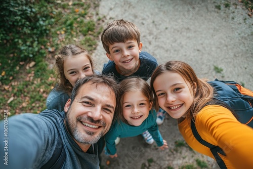 Cheerful father and his three children smiling for a selfie outdoors.