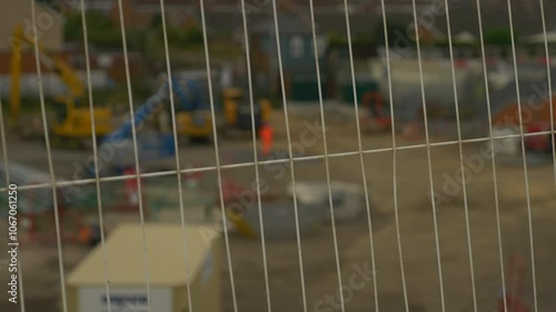 Construction Worker in Orange Work Clothes with Fence in foreground  photo