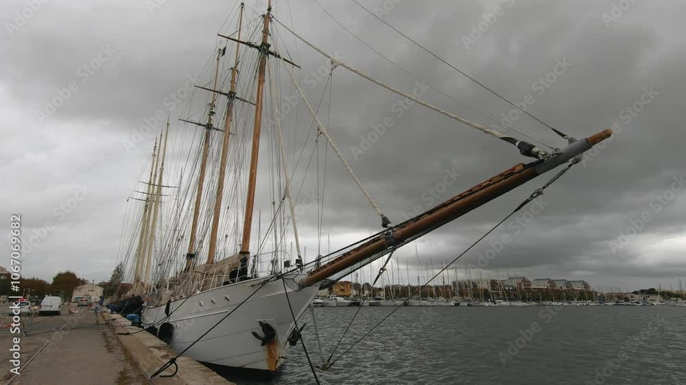 Majestic tall ship docked at harbor on a cloudy day. Vintage sailing vessel with masts and rigging by the calm water, historic maritime scene Majestic tall ship docked at harbor on a cloudy day. Vintage sailing vessel with masts and rigging by the calm water, historic maritime scene