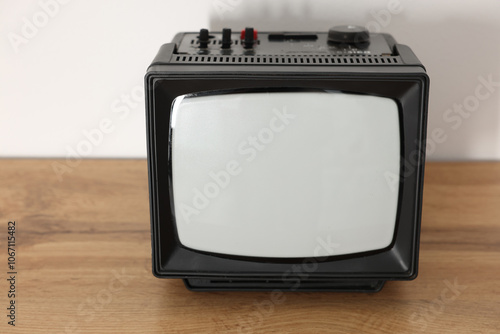 Retro tv set on wooden shelf against white wall photo