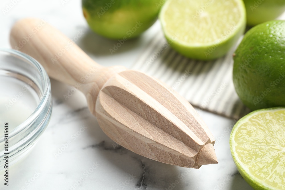 Wooden juicer and fresh limes on white marble table, closeup Wooden juicer and fresh limes on white marble table, closeup