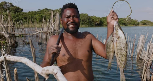 Close-up. Happy smiling fisherman with his fish catch of the day from an ancient traditional woven fishtrap in the Kosi Bay Estuary  photo