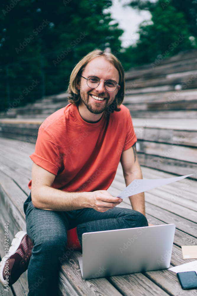 Man smiling at camera sitting in front of laptop on street Man smiling at camera sitting in front of laptop on street