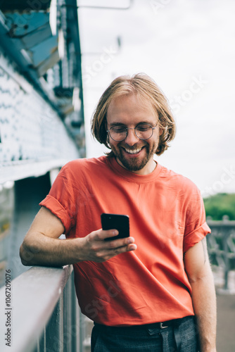 Vászonkép Laughing man in red t shirt surfing smartphone