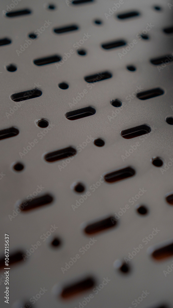 A close-up of a perforated metal surface with a repeating pattern of oval and circular holes. The dark, industrial aesthetic creates a sense of mystery and intrigue. A close-up of a perforated metal surface with a repeating pattern of oval and circular holes. The dark, industrial aesthetic creates a sense of mystery and intrigue.