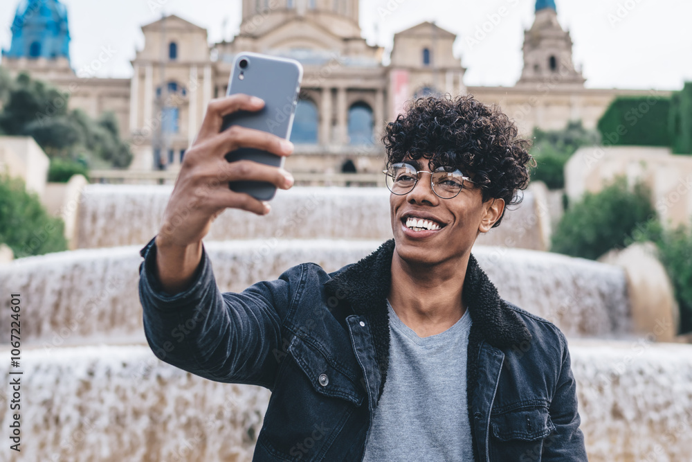 Cheerful black man taking selfie at waterworks edge with smartphone Cheerful black man taking selfie at waterworks edge with smartphone