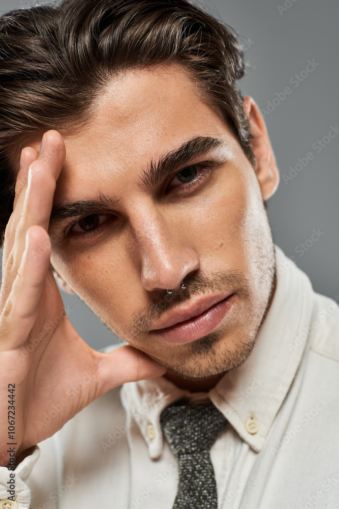 A handsome individual in formal attire strikes a confident pose against a simple grey backdrop, exuding charm. A handsome individual in formal attire strikes a confident pose against a simple grey backdrop, exuding charm.