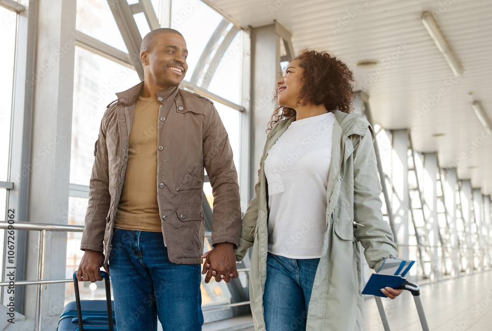 Fototapeta premium african american couple in love going with luggage at airport building, enjoying honeymoon, free space