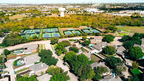 City water tower in fast-growing mixed-use development community of upscale residential houses, tennis center sport complex, park and trail, commercial building Plano downtown background, aerial