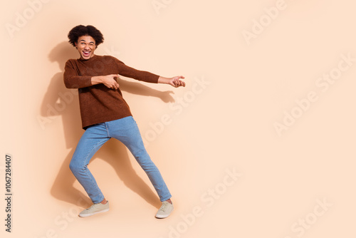 Young man pointing joyfully against beige background, expressing excitement and enthusiasm in casual outfit, perfect for promotional advertising and sales campaigns photo