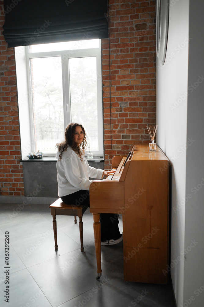 A woman with curly hair sits at a piano, enjoying the music she creates in a well-lit living room featuring cozy furniture. A woman with curly hair sits at a piano, enjoying the music she creates in a well-lit living room featuring cozy furniture.