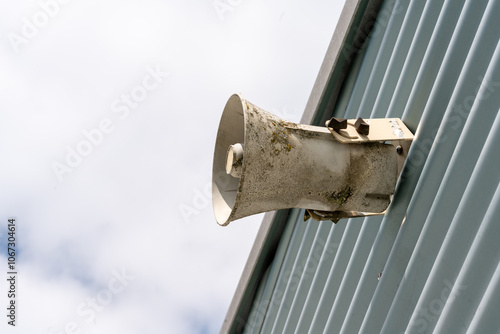 Fotografie Megaphone mounted on a wall as seen from below against a sky with white clouds