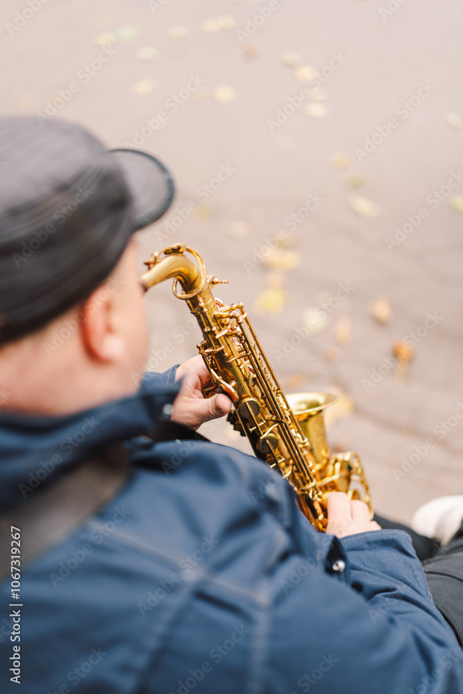 Naklejka premium A saxophonist performs in a serene park during autumn while seated on a bench surrounded by fallen leaves