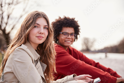 Young mixed race guy and European girl sitting outside along a river hanging out. Munich, Germany photo