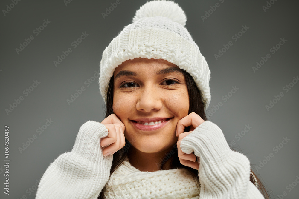 A young woman smiles brightly while wearing a cozy white winter outfit. A young woman smiles brightly while wearing a cozy white winter outfit.