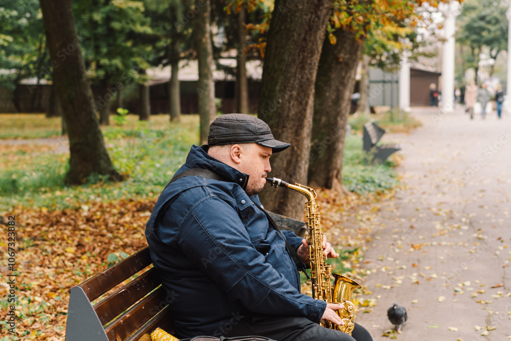 A saxophonist performs in a serene park during autumn while seated on a bench surrounded by fallen leaves A saxophonist performs in a serene park during autumn while seated on a bench surrounded by fallen leaves
