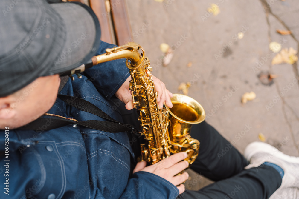 Naklejka premium A saxophonist performs in a serene park during autumn while seated on a bench surrounded by fallen leaves