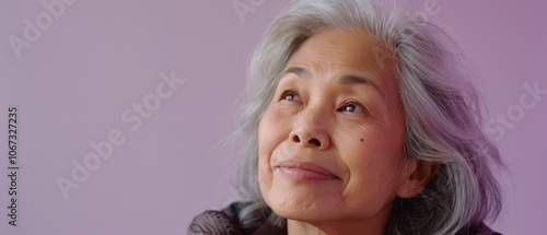 An older woman with glasses stands in front of a chalkboard, her expression a mix of wisdom and authority in an educational setting. photo