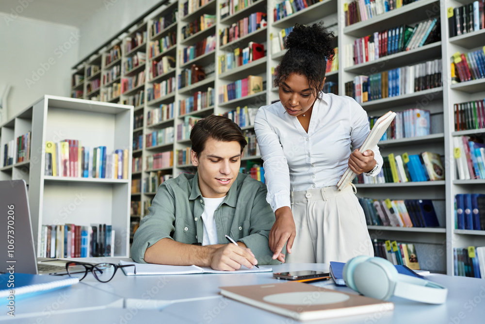 A dedicated teacher assists her student with a focused lesson in a vibrant library. A dedicated teacher assists her student with a focused lesson in a vibrant library.