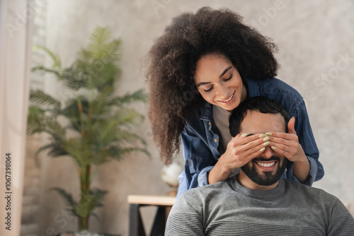 Cuadro en lienzo African woman covering her partner's husband eyes sitting on sofa