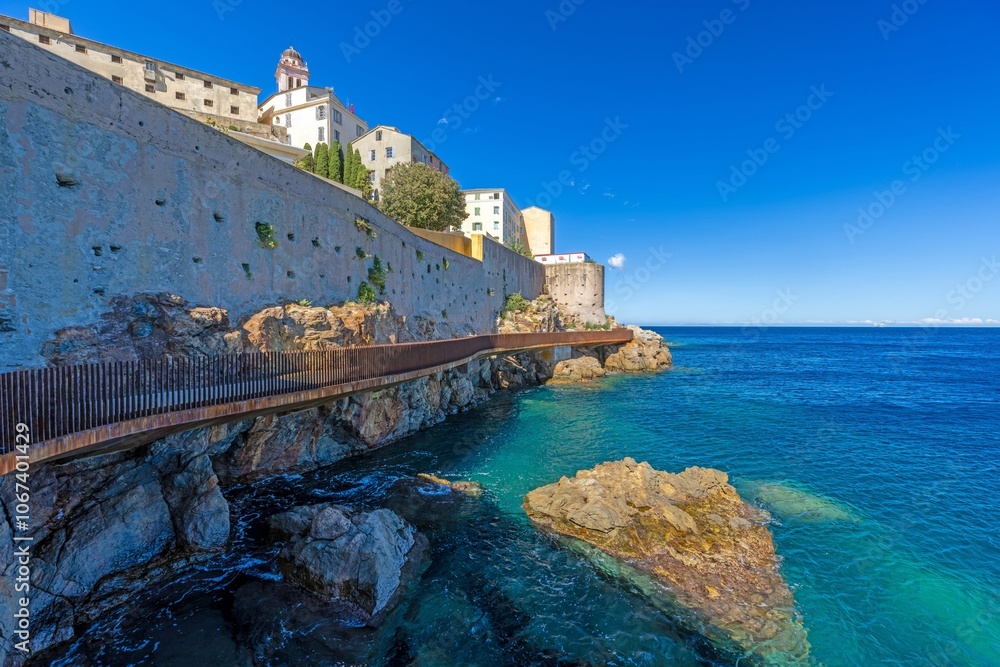 Fototapeta premium Scenic view of Bastia harbor and historic promenade with colorful buildings under a clear blue sky